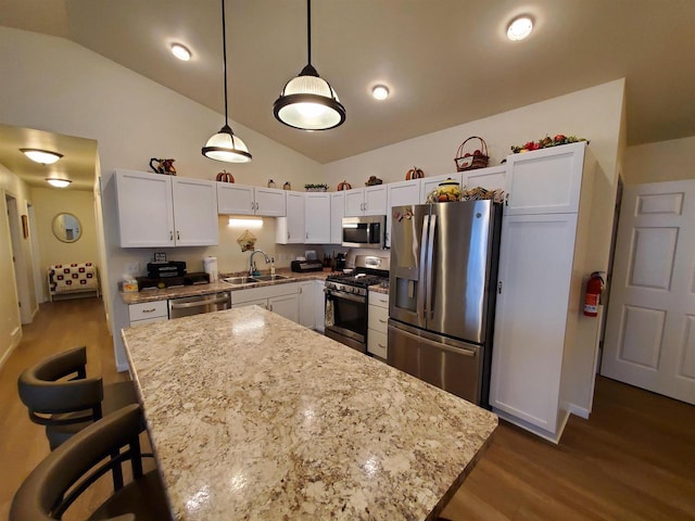 kitchen featuring sink, vaulted ceiling, a kitchen island, white cabinetry, and stainless steel appliances