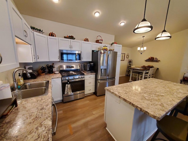 kitchen featuring white cabinets, appliances with stainless steel finishes, decorative light fixtures, and sink