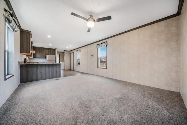 unfurnished living room with ceiling fan, crown molding, and carpet floors