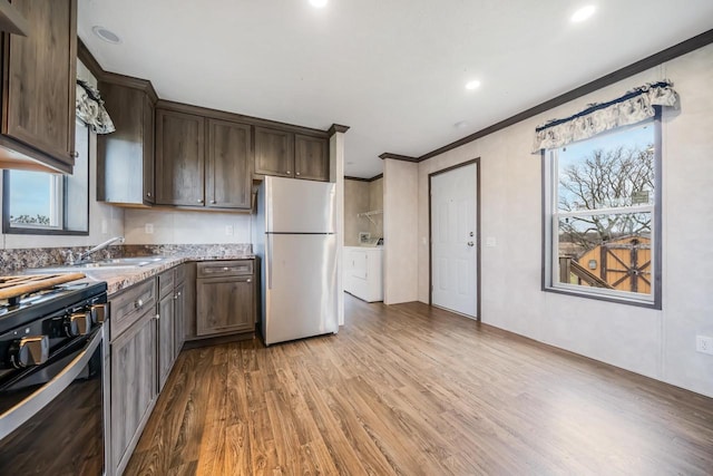 kitchen with plenty of natural light, light stone countertops, light hardwood / wood-style flooring, and fridge