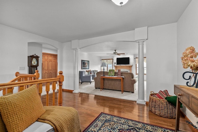 4207 Lost Dauphin Rd, De Pere, WI 54115 - living room featuring ornate columns, a ceiling fan, arched walkways, wood finished floors, and a fireplace