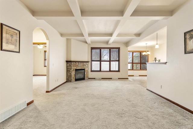 unfurnished living room with beamed ceiling, carpet floors, a stone fireplace, and coffered ceiling