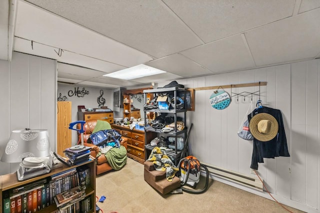 basement featuring wooden walls, carpet floors, and a baseboard radiator