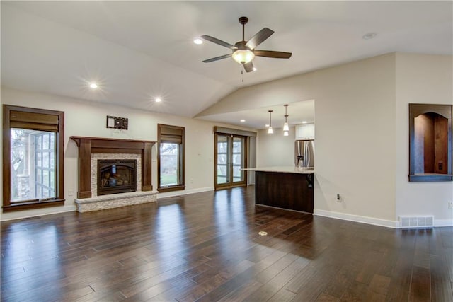 unfurnished living room with lofted ceiling, dark wood-type flooring, ceiling fan, and a healthy amount of sunlight