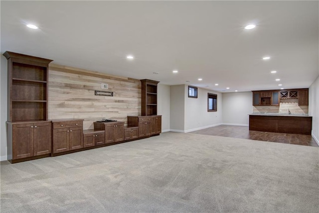 unfurnished living room featuring wood walls and carpet