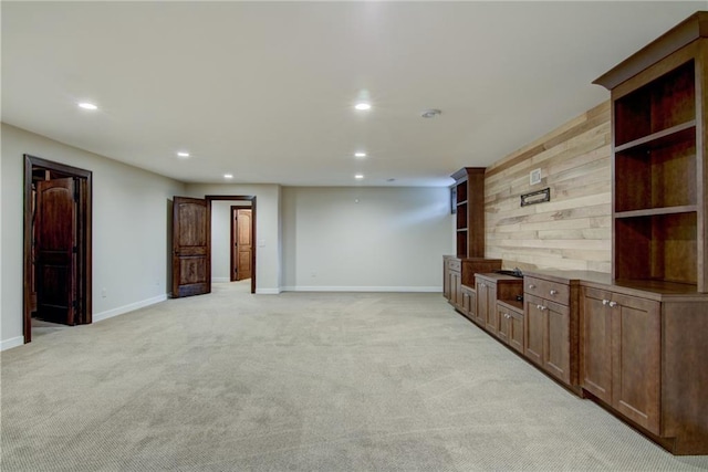 unfurnished living room with wood walls and light carpet