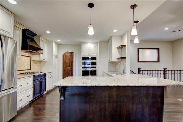 kitchen featuring appliances with stainless steel finishes, premium range hood, dark wood-type flooring, sink, and pendant lighting