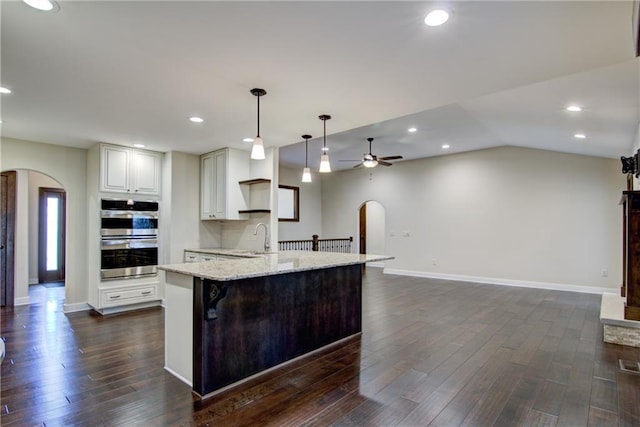 kitchen featuring dark hardwood / wood-style flooring, light stone countertops, pendant lighting, and stainless steel double oven