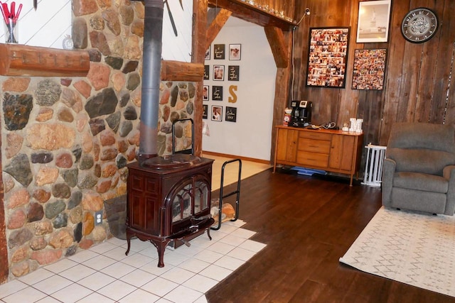 living room featuring radiator, a wood stove, wooden walls, and light hardwood / wood-style flooring