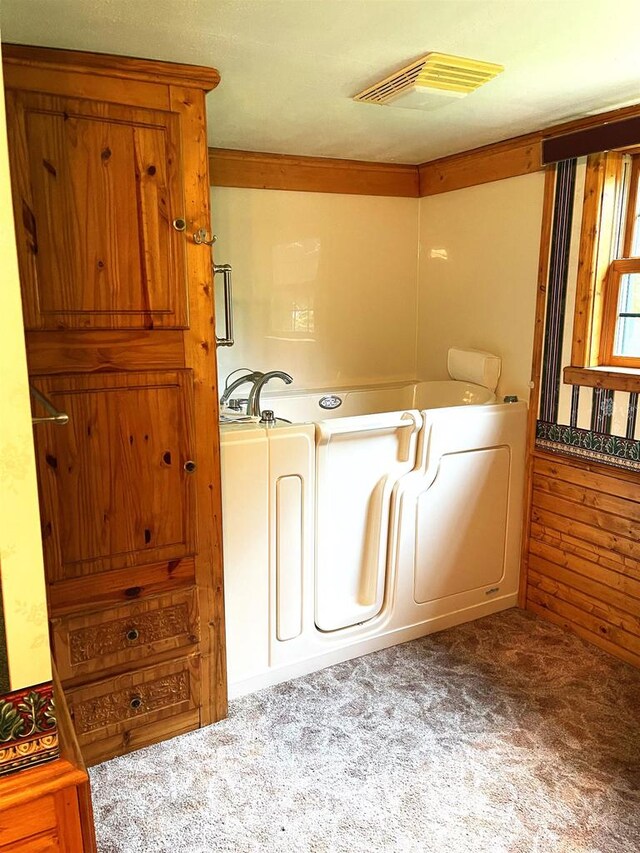 bathroom featuring a washtub and wooden walls