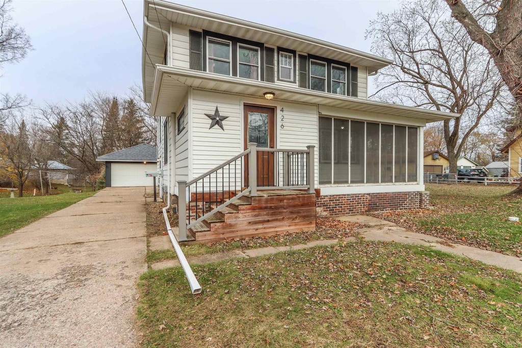 view of front of house featuring a sunroom, a garage, and an outbuilding