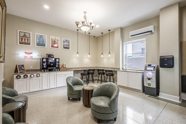 kitchen with light stone countertops, an inviting chandelier, a wall mounted AC, pendant lighting, and white cabinets