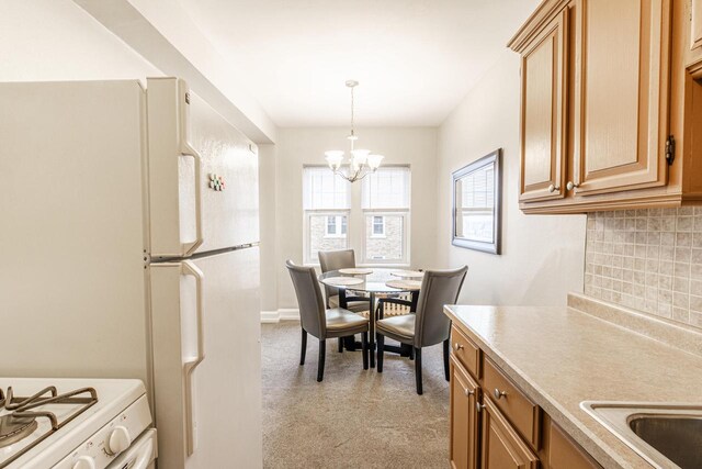 kitchen with a chandelier, pendant lighting, white appliances, and backsplash