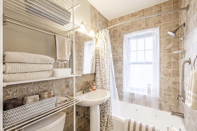 bathroom featuring tasteful backsplash, shower / tub combo, tile walls, and toilet