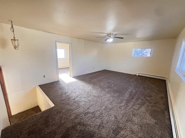 carpeted empty room featuring ceiling fan and a baseboard heating unit