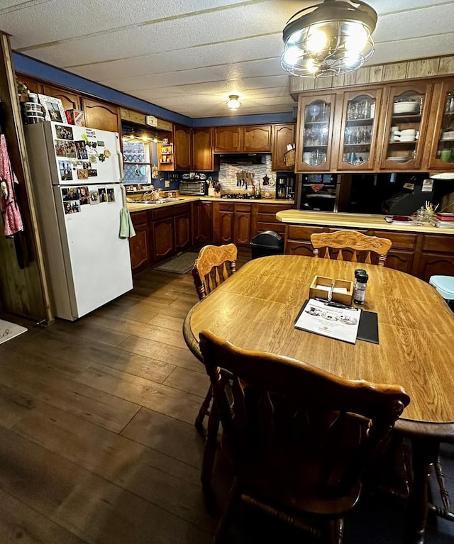 kitchen featuring decorative backsplash, stainless steel gas cooktop, dark wood-type flooring, sink, and white refrigerator