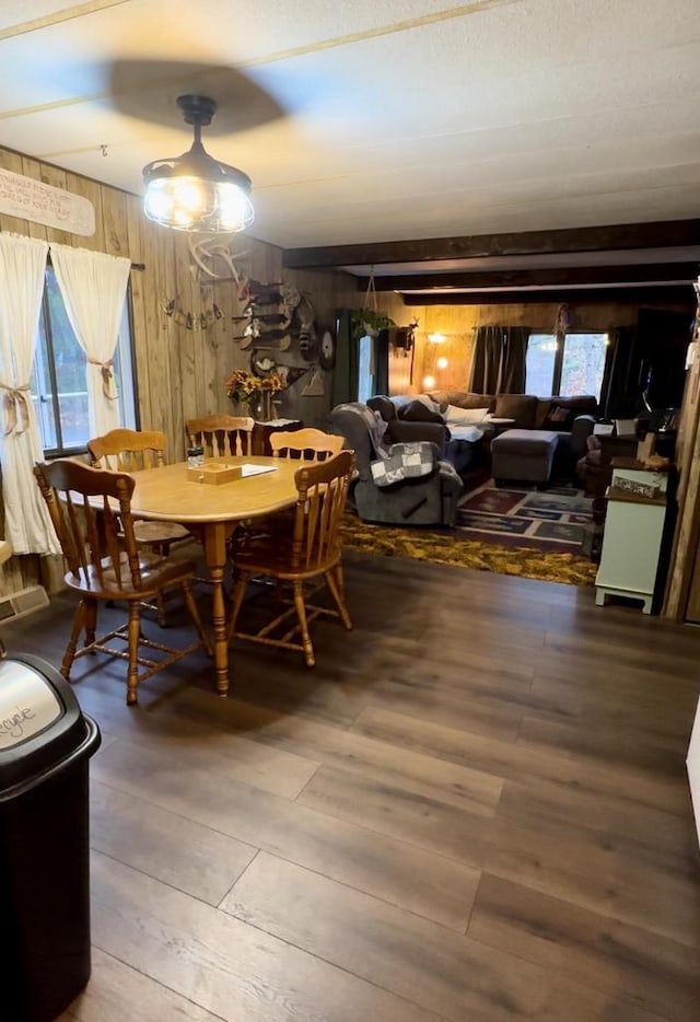 dining room featuring hardwood / wood-style flooring, beam ceiling, and wood walls