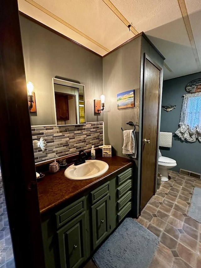 bathroom with tasteful backsplash, vanity, a textured ceiling, and toilet