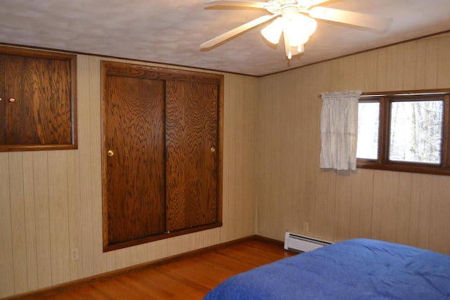 bedroom with hardwood / wood-style floors, ceiling fan, and wood walls