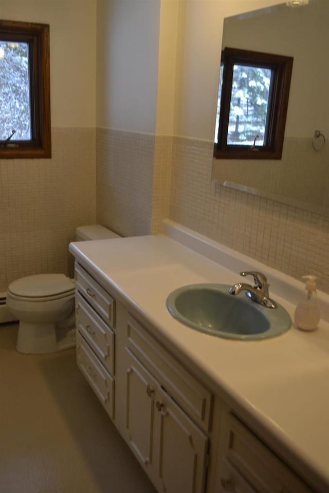 bathroom with vanity, toilet, and tile walls