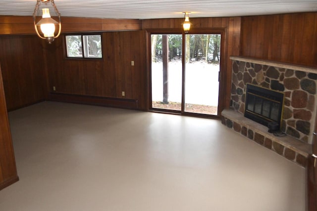 unfurnished living room with wood walls, a stone fireplace, and a baseboard radiator