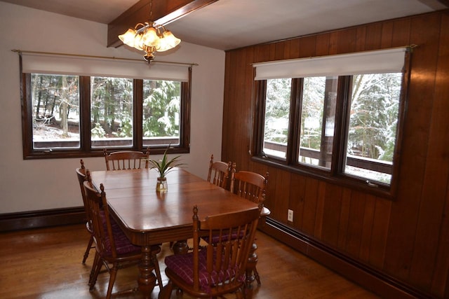 dining area with wood walls, wood-type flooring, and a baseboard heating unit