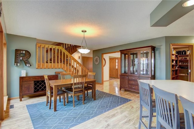 dining room with light hardwood / wood-style floors and a textured ceiling