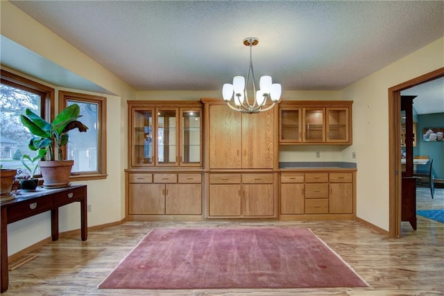 dining area with light hardwood / wood-style floors, a textured ceiling, and a notable chandelier