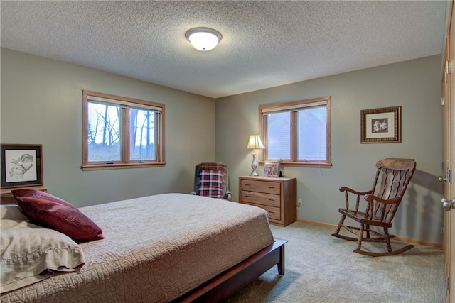 bedroom with multiple windows, light colored carpet, and a textured ceiling