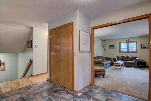 hall featuring dark colored carpet and a textured ceiling