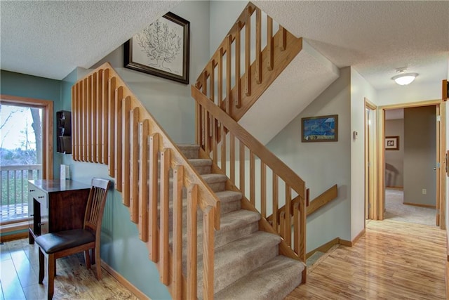 staircase featuring hardwood / wood-style flooring, lofted ceiling, and a textured ceiling