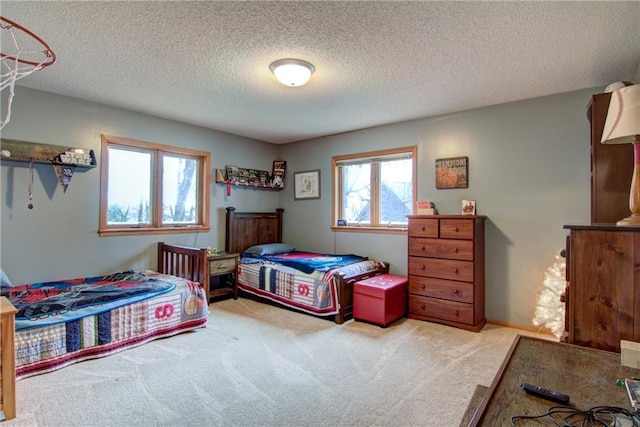 bedroom with multiple windows, light carpet, and a textured ceiling