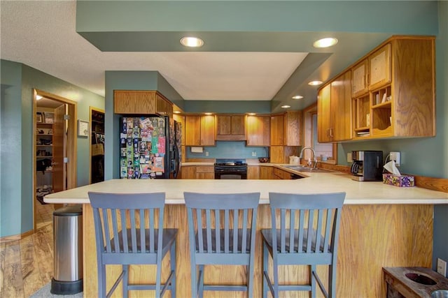 kitchen with black appliances, a kitchen bar, kitchen peninsula, and sink