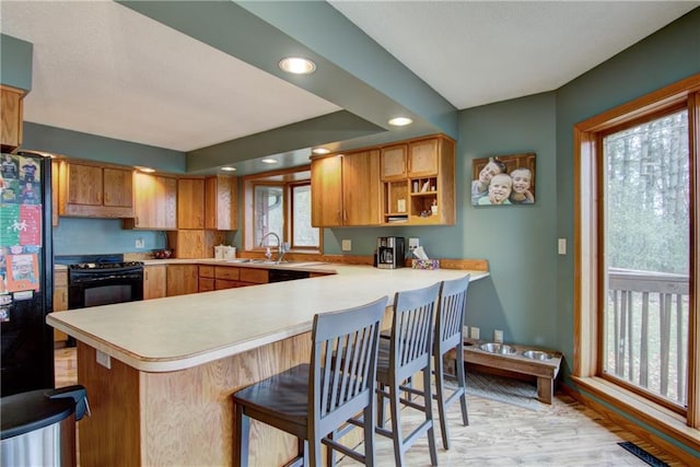 kitchen with kitchen peninsula, a healthy amount of sunlight, and a breakfast bar area