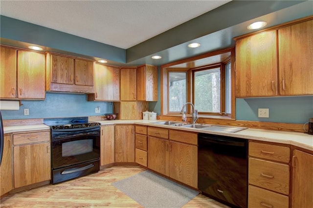 kitchen featuring black appliances, sink, and light hardwood / wood-style flooring