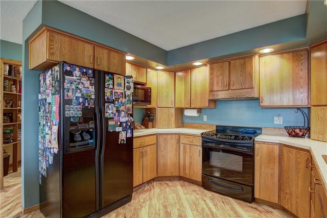 kitchen with a textured ceiling, light hardwood / wood-style flooring, and black appliances