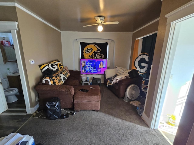 carpeted living room with ceiling fan and ornamental molding