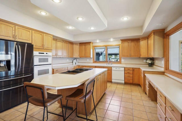 kitchen featuring sink, a kitchen breakfast bar, light tile patterned flooring, a kitchen island, and appliances with stainless steel finishes