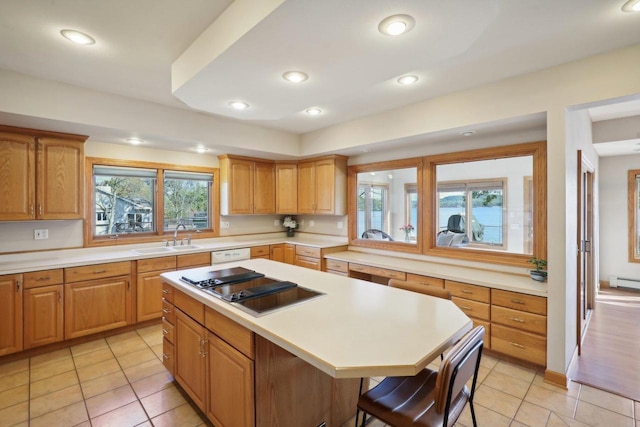 kitchen with a center island, sink, a kitchen breakfast bar, black cooktop, and light tile patterned flooring