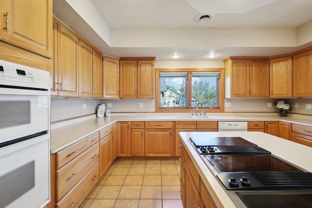 kitchen featuring light tile patterned floors, white appliances, and sink