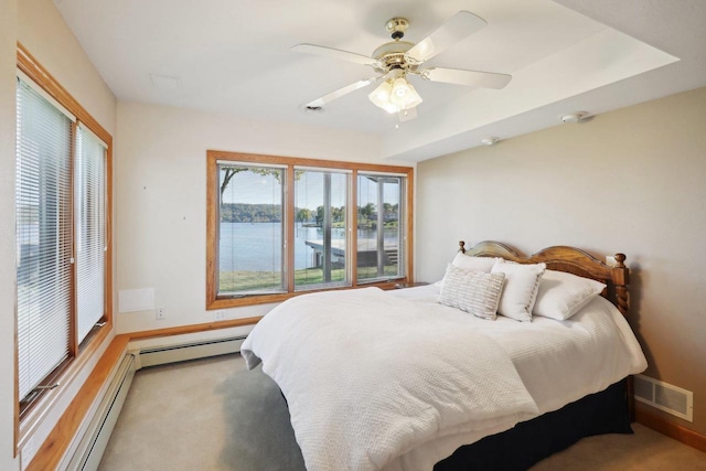 bedroom with a water view, baseboard heating, ceiling fan, and light colored carpet