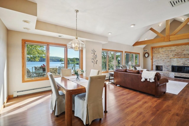 dining space with a healthy amount of sunlight, a water view, a brick fireplace, and a baseboard heating unit