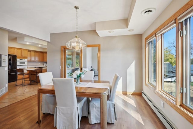 dining area featuring light wood-type flooring, an inviting chandelier, and baseboard heating