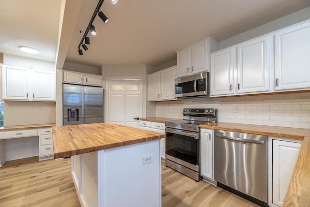 kitchen with appliances with stainless steel finishes, light hardwood / wood-style floors, white cabinets, a center island, and butcher block countertops