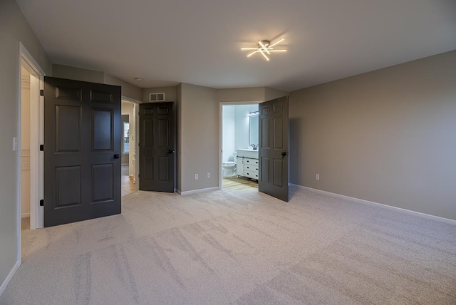 unfurnished bedroom with ensuite bath, sink, and light colored carpet