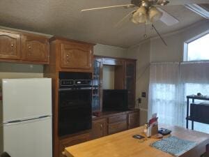 kitchen featuring double oven, ceiling fan, and white refrigerator