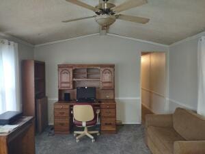 office area featuring dark colored carpet, vaulted ceiling, and ceiling fan