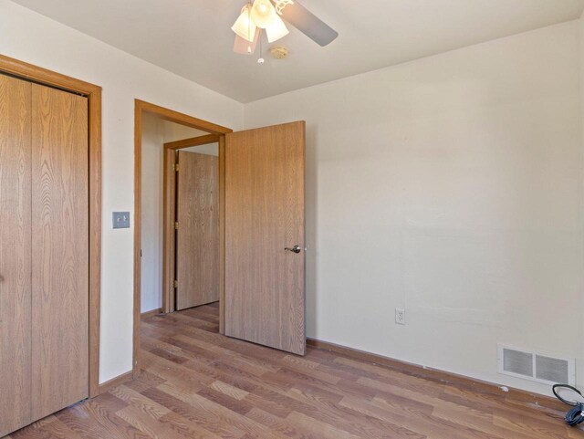 unfurnished bedroom featuring ceiling fan, a closet, and light hardwood / wood-style flooring