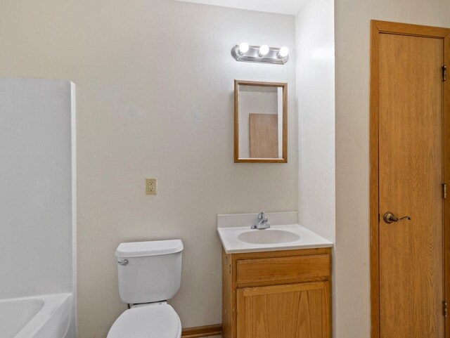 bathroom with a bath, vanity, and toilet