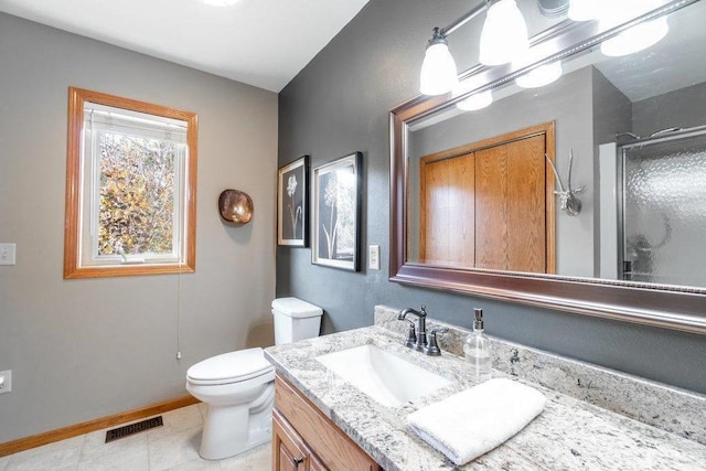 bathroom featuring tile patterned floors, vanity, a shower with shower door, and toilet